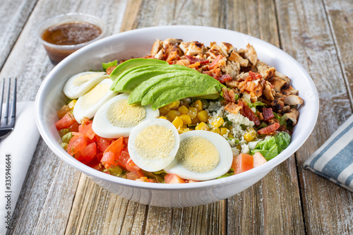 A view of a bowl of cobb salad, in a restaurant or kitchen setting.
