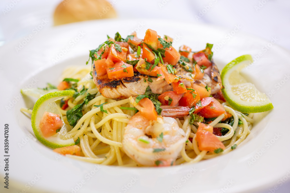 A view of an Italian spaghetti dish with Salmon and shrimp, in a restaurant or kitchen setting.