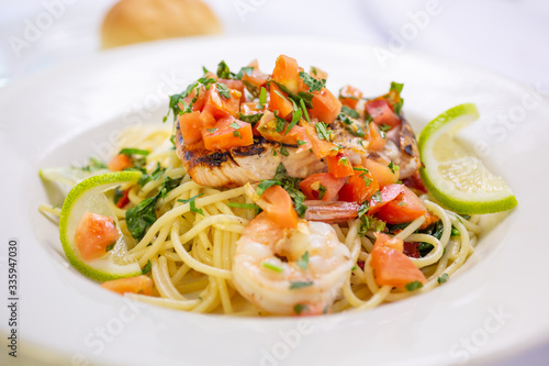 A view of an Italian spaghetti dish with Salmon and shrimp, in a restaurant or kitchen setting.