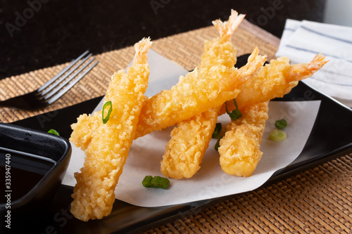 A closeup view of an appetizer plate of tempura shrimp, in a restaurant or kitchen setting.