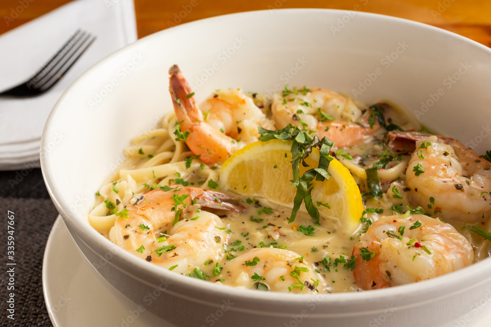 A closeup view of a bowl of shrimp scampi, in a restaurant or kitchen setting.