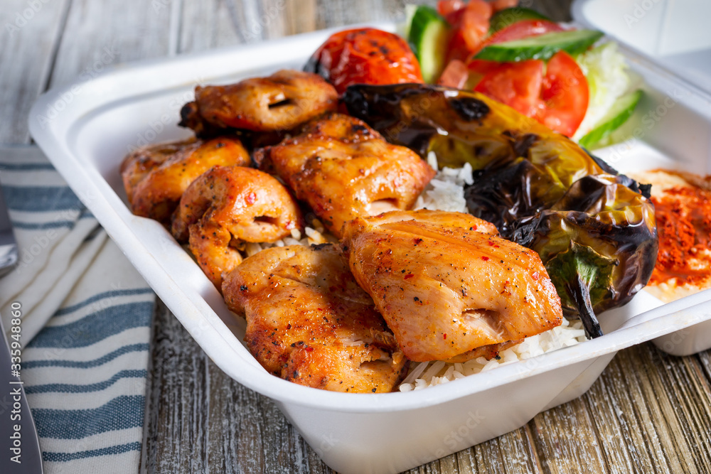 A view of a combo plate featuring Mediterranean chicken thighs, in a restaurant or kitchen setting. A view of a combo plate featuring Mediterranean chicken thighs, in a restaurant or kitchen setting.