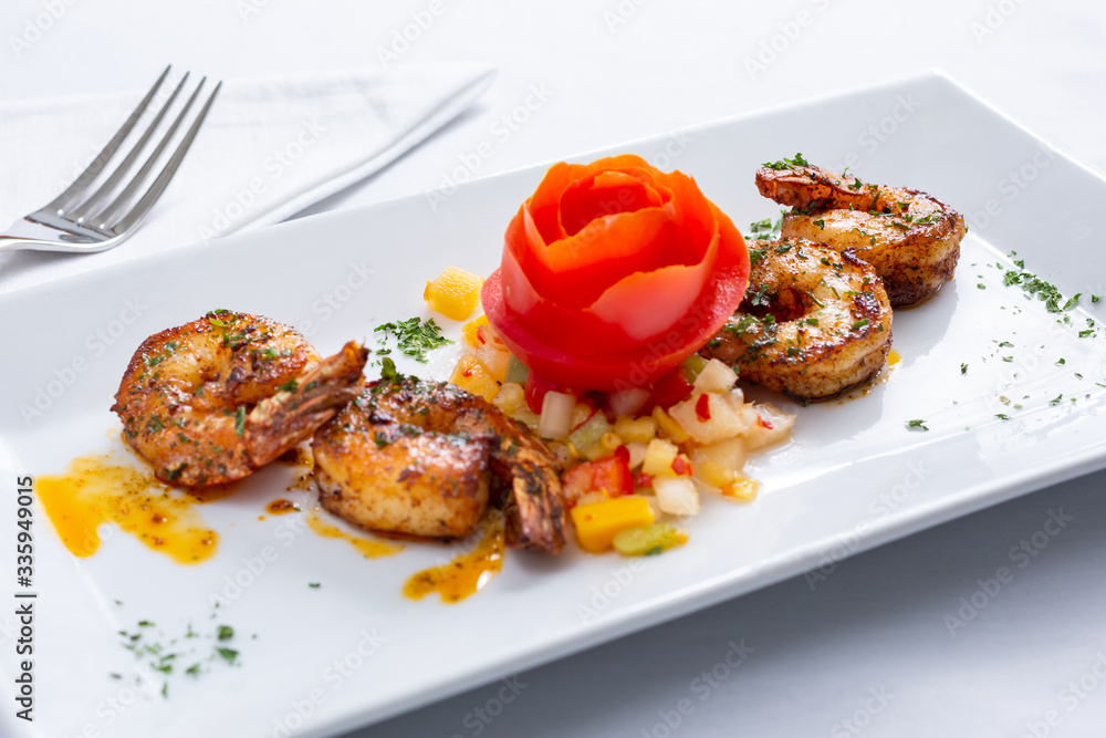 A view of a plate of grilled shrimp, in a restaurant or kitchen setting.