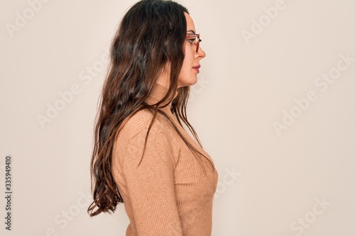 Young beautiful woman wearing casual turtleneck sweater and glasses over white background looking to side, relax profile pose with natural face with confident smile.