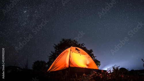 Time laps of milky way and stars of night clear sky above mountain with camping tent located north of Thailand