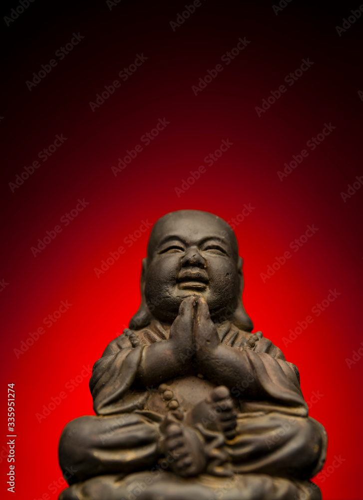 A small replica statue of The Buddha with a red background