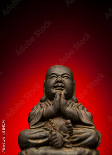 A small replica statue of The Buddha with a red background