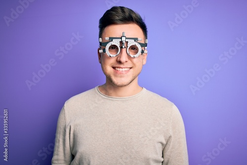 Young handsome caucasian man wearing optometrical glasses over purple background with a happy and cool smile on face. Lucky person.