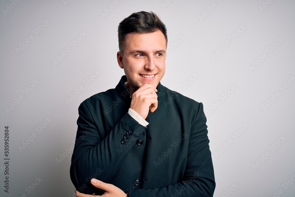 Young handsome business mas wearing elegant winter coat standing over isolated background with hand on chin thinking about question, pensive expression. Smiling with thoughtful face. Doubt concept. Young handsome business mas wearing elegant winter coat standing over isolated background with hand on chin thinking about question, pensive expression. Smiling with thoughtful face. Doubt concept.