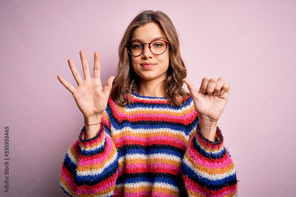 Young beautiful blonde girl wearing glasses and casual sweater over pink isolated background showing and pointing up with fingers number six while smiling confident and happy. Young beautiful blonde girl wearing glasses and casual sweater over pink isolated background showing and pointing up with fingers number six while smiling confident and happy.