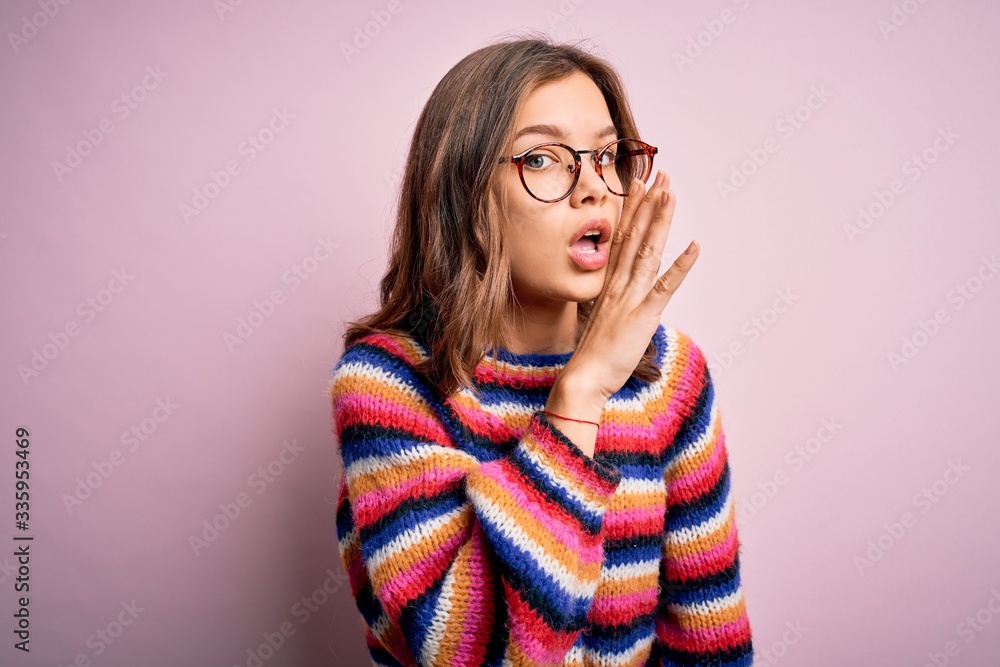 Young beautiful blonde girl wearing glasses and casual sweater over pink isolated background hand on mouth telling secret rumor, whispering malicious talk conversation