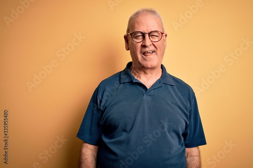 Middle age handsome hoary man wearing casual polo and glasses over yellow background winking looking at the camera with sexy expression, cheerful and happy face. © Krakenimages.com