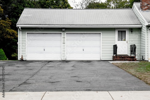 A two cars garage doors painted in white color on a typical single house.