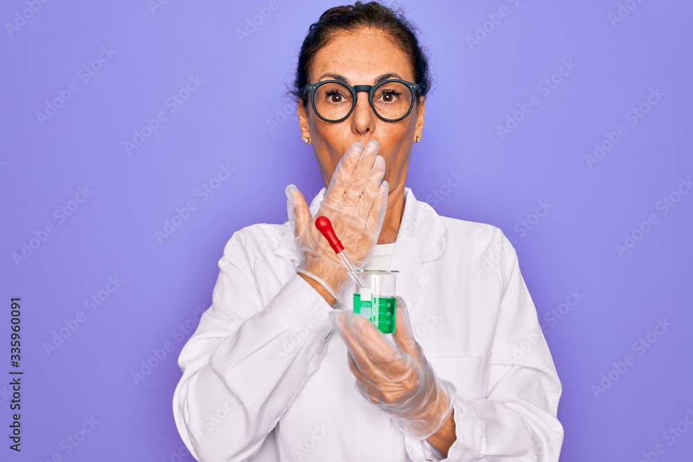 Middle age senior scientist woman wearing laboratory coat holding research test tube cover mouth with hand shocked with shame for mistake, expression of fear, scared in silence, secret concept Middle age senior scientist woman wearing laboratory coat holding research test tube cover mouth with hand shocked with shame for mistake, expression of fear, scared in silence, secret concept