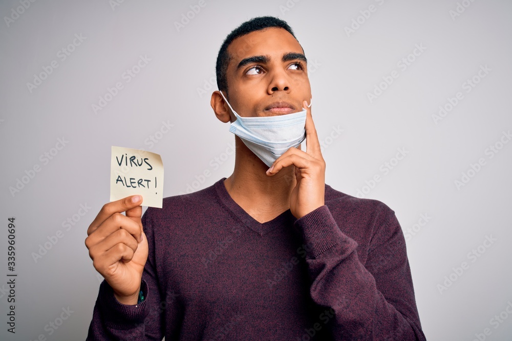 Young handsome african american man wearing medical mask holding virus alert reminder serious face thinking about question, very confused idea Young handsome african american man wearing medical mask holding virus alert reminder serious face thinking about question, very confused idea