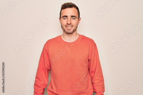 Young handsome man with blue eyes wearing casual sweater standing over white background with a happy and cool smile on face. Lucky person. © Krakenimages.com