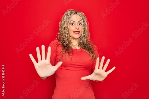 Wallpaper Mural Young beautiful blonde woman wearing red casual t-shirt standing over isolated background afraid and terrified with fear expression stop gesture with hands, shouting in shock. Panic concept. Torontodigital.ca