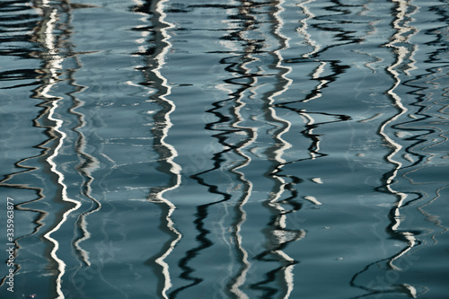 Reflection of masts of sailboats on water, interesting texture, smooth lines of water, a sail regatta, reflection of masts on water, ropes and aluminum, Bright colors