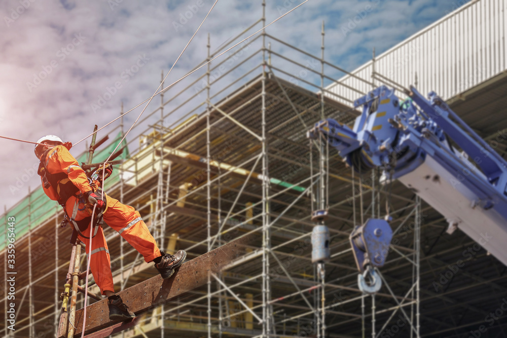 Fototapeta premium Rope access Safety sprinkling worker on high with scaffolding wear dresses and safety man with harness safety concept in site construction building with copy space on staging background.