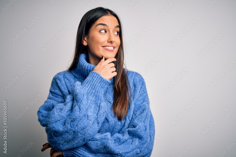 Young beautiful brunette woman wearing casual turtleneck sweater over white background with hand on chin thinking about question, pensive expression. Smiling with thoughtful face. Doubt concept. Young beautiful brunette woman wearing casual turtleneck sweater over white background with hand on chin thinking about question, pensive expression. Smiling with thoughtful face. Doubt concept.