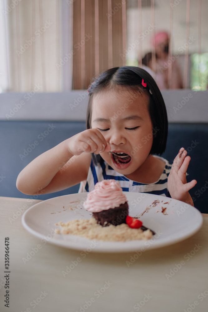 A girl eating happily with a strawberry whipped cream. 4 year old daughter Celebrating a birthday with a chocolate lava dessert A girl eating happily with a strawberry whipped cream. 4 year old daughter Celebrating a birthday with a chocolate lava dessert