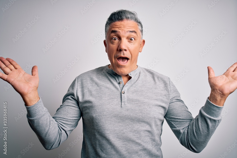 Middle age handsome grey-haired man wearing casual t-shirt over white background celebrating crazy and amazed for success with arms raised and open eyes screaming excited. Winner concept Middle age handsome grey-haired man wearing casual t-shirt over white background celebrating crazy and amazed for success with arms raised and open eyes screaming excited. Winner concept
