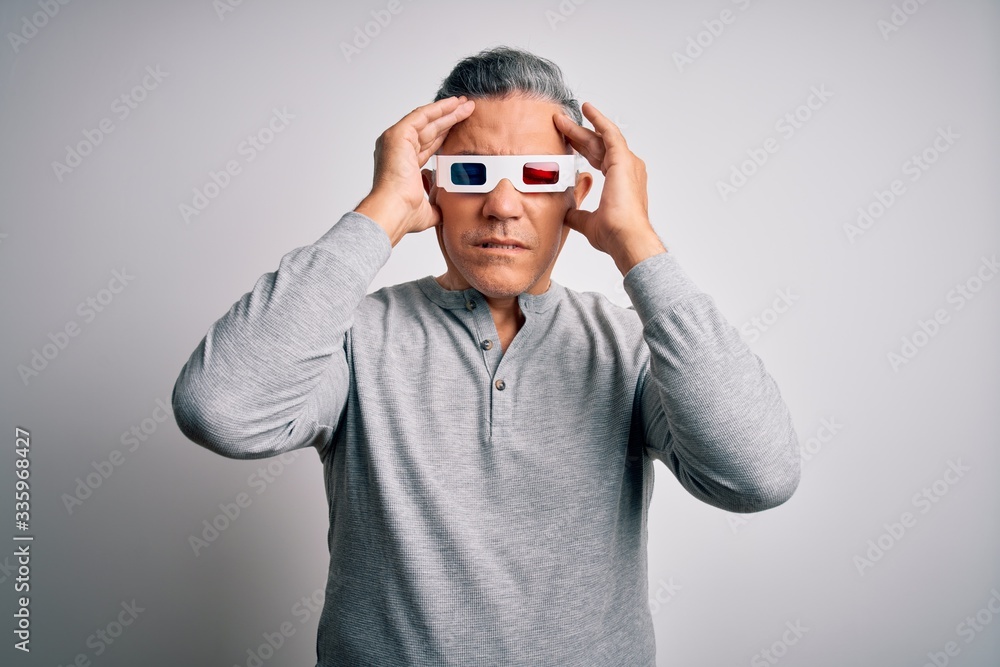 Middle age handsome grey-haired man using 3d glasses over isolated white background suffering from headache desperate and stressed because pain and migraine. Hands on head. Middle age handsome grey-haired man using 3d glasses over isolated white background suffering from headache desperate and stressed because pain and migraine. Hands on head.