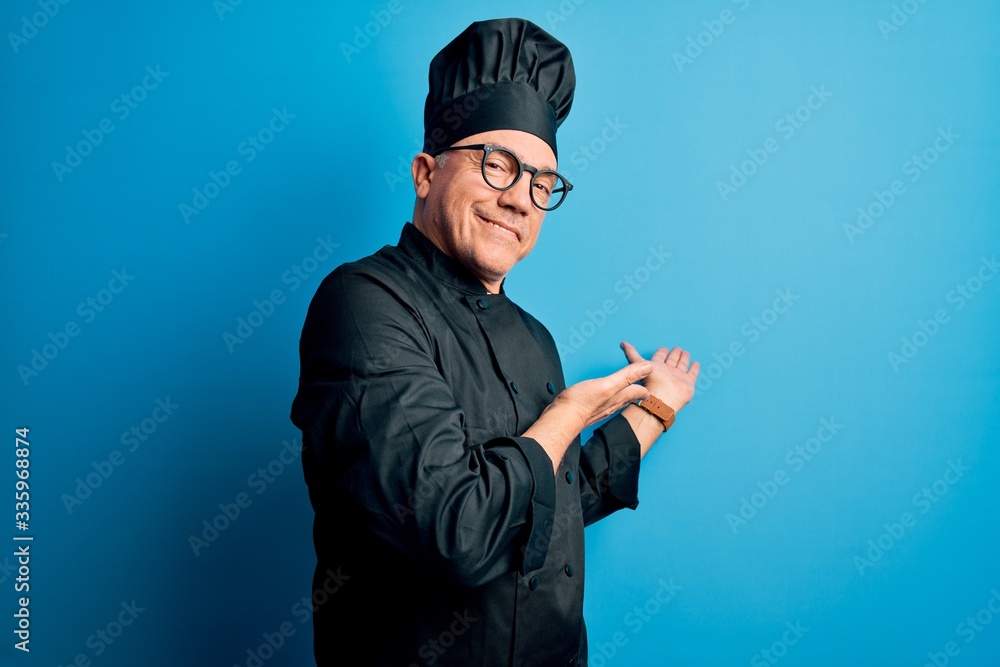 Middle age handsome grey-haired chef man wearing cooker uniform and hat Inviting to enter smiling natural with open hand Middle age handsome grey-haired chef man wearing cooker uniform and hat Inviting to enter smiling natural with open hand