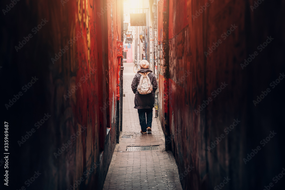 Ταπετσαρία Traveler girl leaves narrow long red corridor or tunnel on city street, rear view