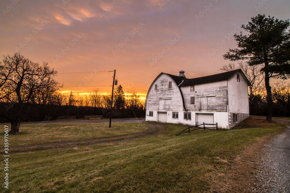 A white barn in a public park during a colorful country sunrise