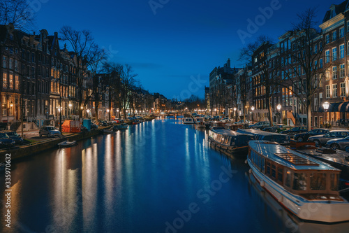 Amsterdam night city skyline at water canal waterfront with boat houses, Amsterdam, Netherlands.