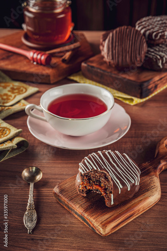 Foto A bitte honey cookie chocolate covered on the wooden table with a porcelain cup