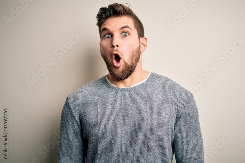 Young handsome blond man with beard and blue eyes wearing casual sweater afraid and shocked with surprise expression, fear and excited face. © Krakenimages.com