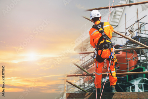Obraz na plátně Double exposure worker on height at scaffolding in construction site symbol foot for building, wearing equipment protective full safety harness with safety helmet and PPE