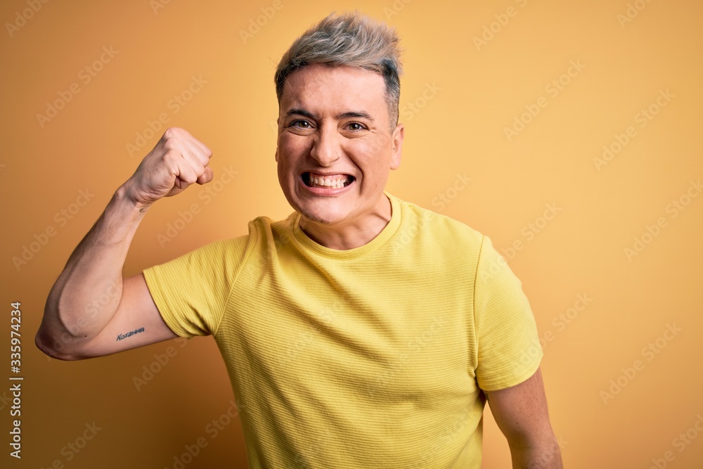 Young handsome modern man wearing yellow shirt over yellow isolated background angry and mad raising fist frustrated and furious while shouting with anger. Rage and aggressive concept. Young handsome modern man wearing yellow shirt over yellow isolated background angry and mad raising fist frustrated and furious while shouting with anger. Rage and aggressive concept.