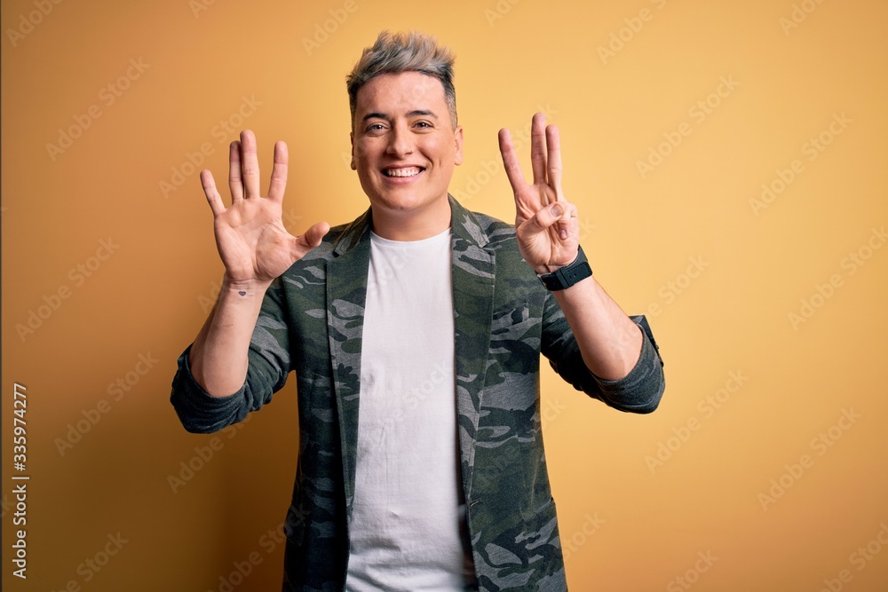 Fototapeta premium Young handsome modern man wearing business jacket standing over yellow isolated background showing and pointing up with fingers number eight while smiling confident and happy.