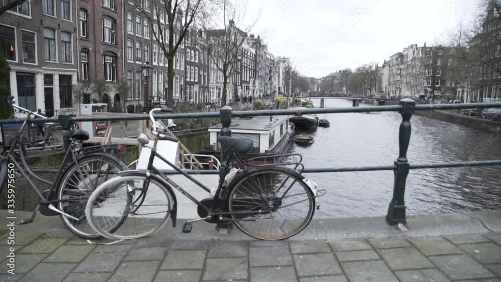 Typical sight of a bike standing against a bridge in Amsterdam with canals on the background slow motion Typical sight of a bike standing against a bridge in Amsterdam with canals on the background slow motion