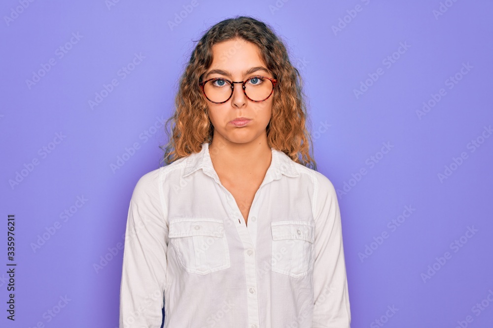 Young beautiful woman with blue eyes wearing casual shirt and glasses over purple background depressed and worry for distress, crying angry and afraid. Sad expression. Young beautiful woman with blue eyes wearing casual shirt and glasses over purple background depressed and worry for distress, crying angry and afraid. Sad expression.