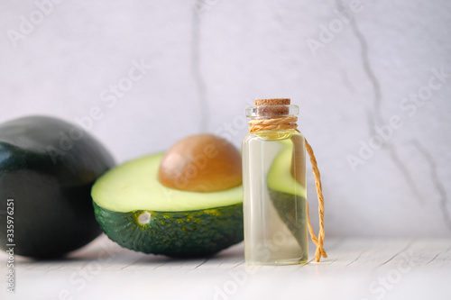 Avocado oil and fresh avocado on table close-up.