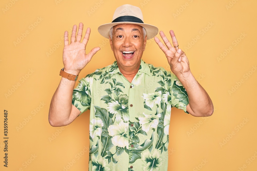 Middle age senior grey-haired man wearing summer hat and floral shirt on beach vacation showing and pointing up with fingers number eight while smiling confident and happy. Middle age senior grey-haired man wearing summer hat and floral shirt on beach vacation showing and pointing up with fingers number eight while smiling confident and happy.