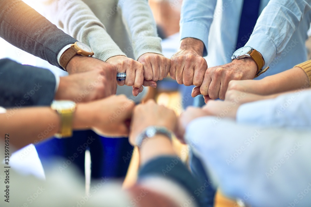 Fototapeta premium Group of business workers standing bumping fists at the office