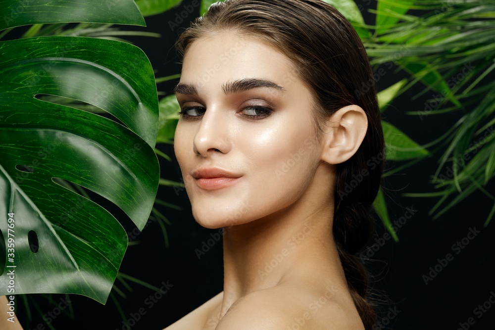 Beautiful woman bare shoulders clean skin green leaves Beautiful woman bare shoulders clean skin green leaves