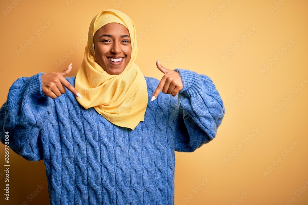 Young African American afro woman wearing muslim hijab over isolated yellow background looking confident with smile on face, pointing oneself with fingers proud and happy. Young African American afro woman wearing muslim hijab over isolated yellow background looking confident with smile on face, pointing oneself with fingers proud and happy.