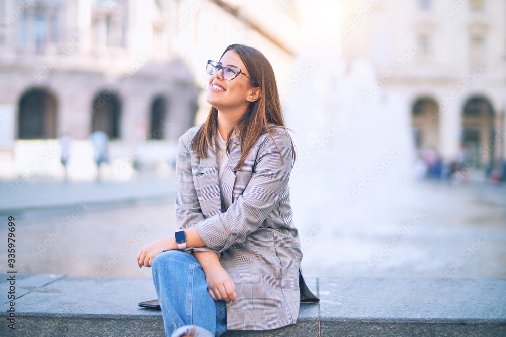 Fototapeta premium Young beautiful woman smiling happy and confident. Sitting with smile on face at the town street