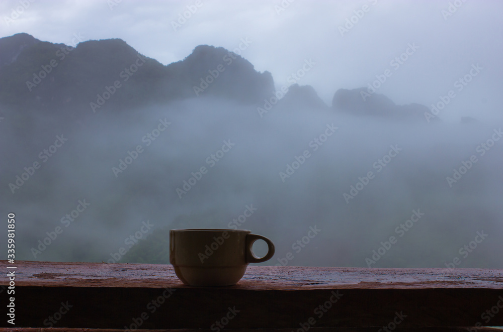 cup of coffee on the table with white fog mountain in background