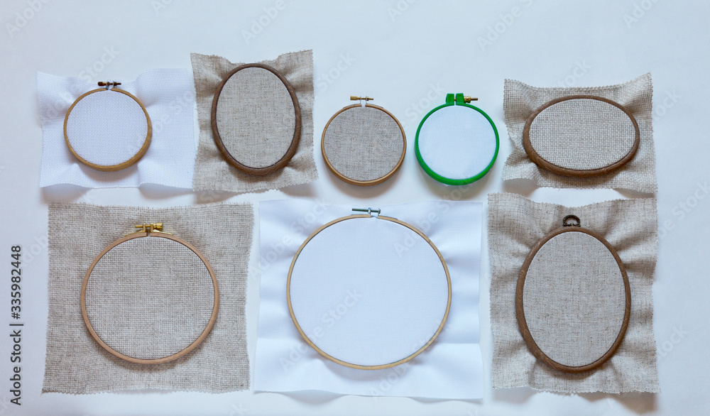 Needlework and embroidery. Round and oval hoops for cross-stitch with special square-mesh fabric of natural cotton and linen. Flat lay, copy space, top view, close-up Needlework and embroidery. Round and oval hoops for cross-stitch with special square-mesh fabric of natural cotton and linen. Flat lay, copy space, top view, close-up