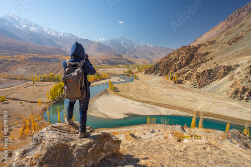 A photographer with backpack taking picture of mountain and autumn trees in Phander valley, Gilgit Baltistan in Pakistan photo
