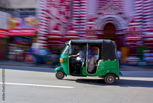Abstracted Panning Photography Of A Three Wheeler In Front Of Red Mosque In Colombo, Sri Lanka. Tuk Tuk Can Be Found On All Roads In Sri Lanka That Transporting Locals, Foreigners, Or Freights
