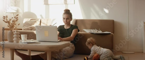 Caucasian mother working from home, having a work video call, daughter playing nearby. Stay home, quarantine remote work. Shot on RED Dragon photo