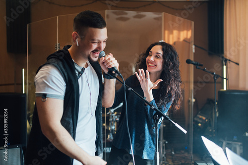 A man at a vocal lesson sings and makes mistakes, teacher laughs showing a gesture of indignation